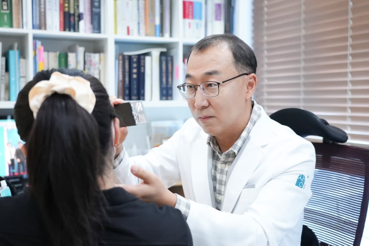 생기한의원 창원점 송성문 원장이 진료실에서 내원자의 얼굴 피부를 살피는 진료 장면